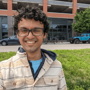 Indian male with black hair, and black-rimmed rectangular glasses.